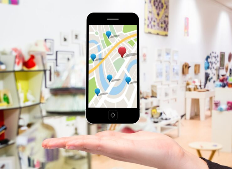 composite of hand holding smartphone with maps graphic with store background